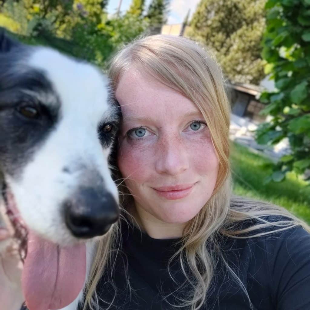 Hundetrainerin Sonja und Border Collie Hündin Leela blicken nebeneinander direkt in die Kamera beim Training an einem Sommertag in der Hundeschule Hof.
